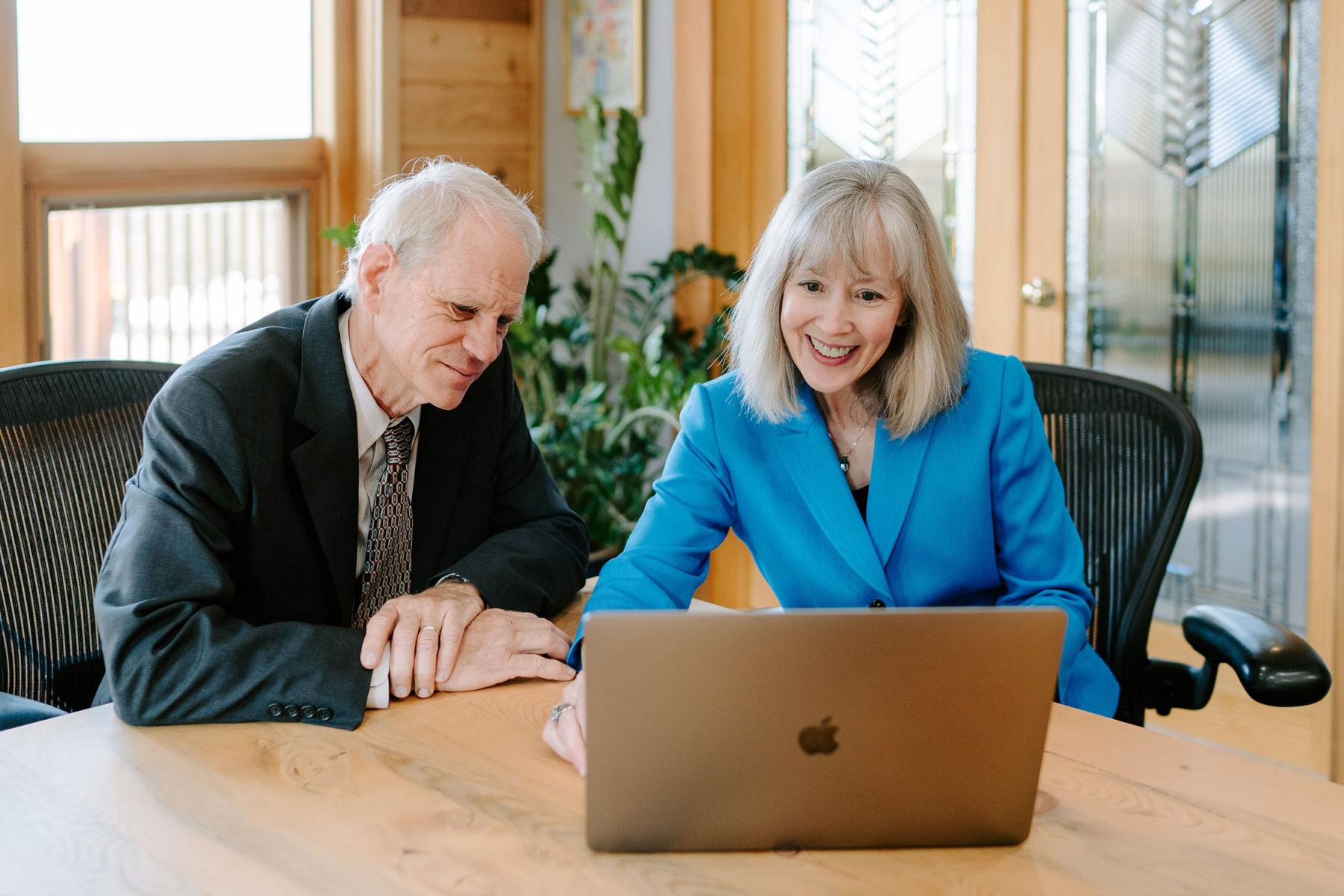 Two people looking at a laptop and smiling