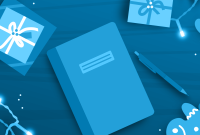 A journal and pen surrounded by gifts, string lights, and cookies